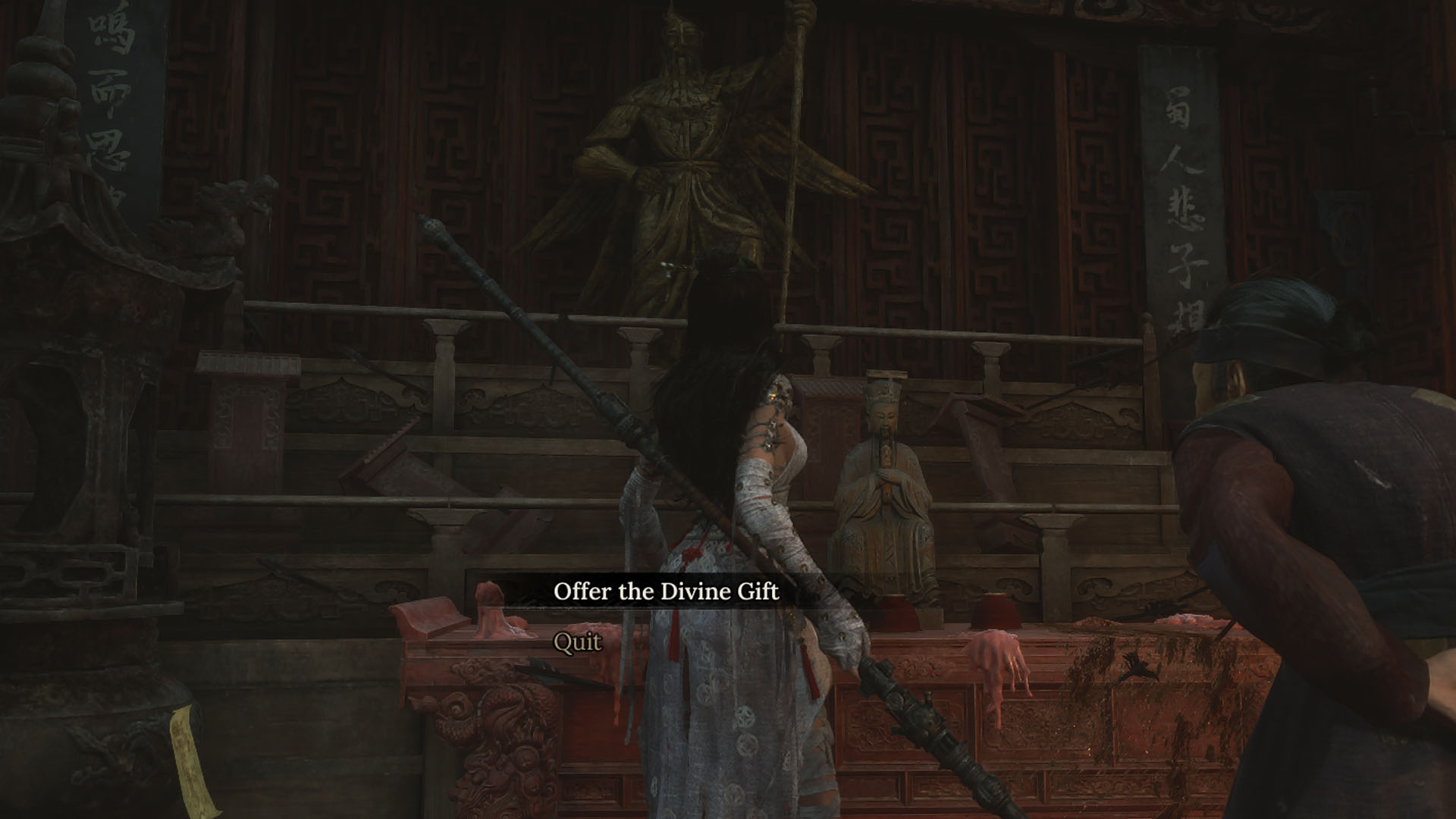 A Wuchang: Fallen Feathers screenshot showing the main character interacting with a statue. You can see a menu giving the player the option to offer the Divine Gift to the statue. There’s a old lady beside the main character.